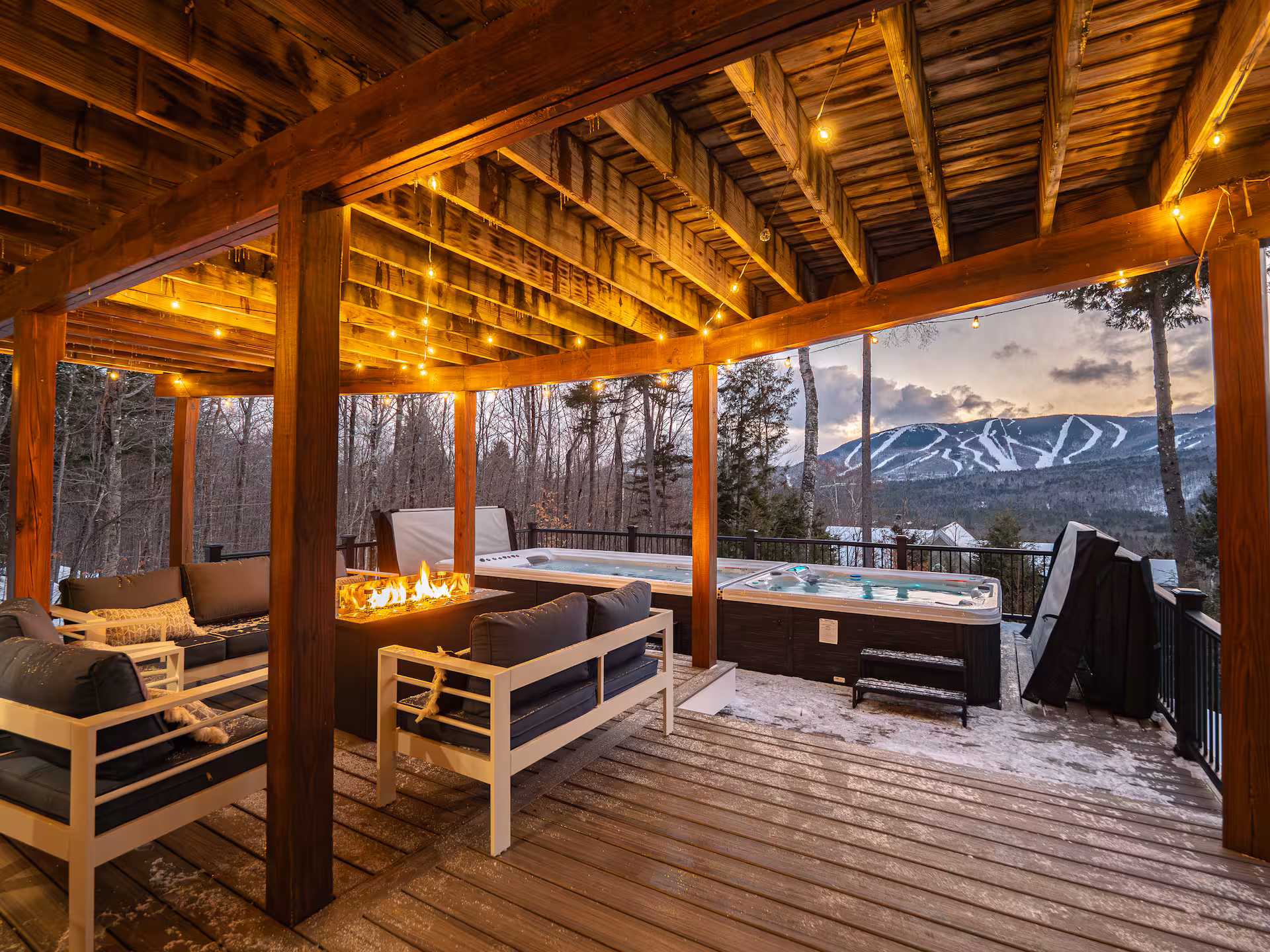 Covered outdoor deck with pool, hot tub, lounge seating, and mountain view.